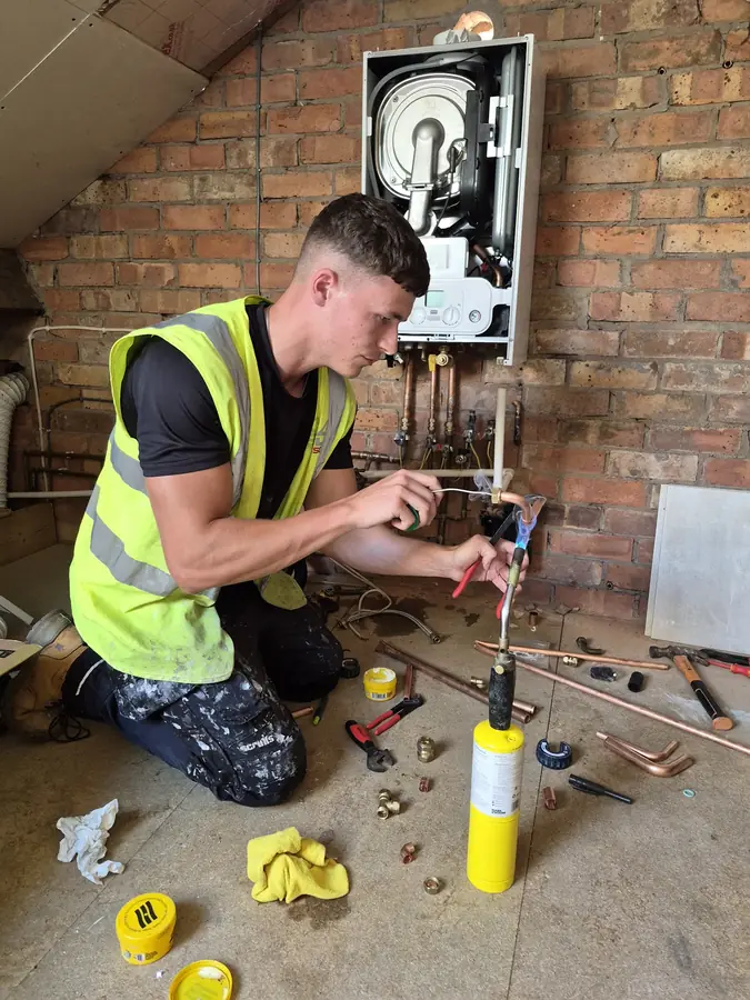 Engineer soldering copper pipework during a boiler installation